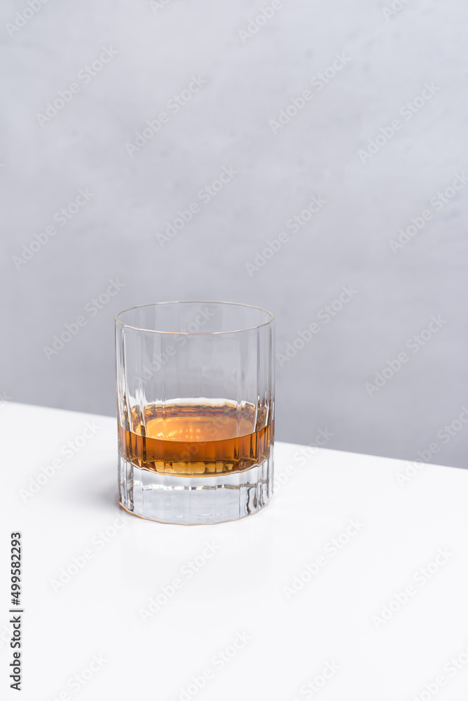 Un vaso de whisky sobre una mesa blanca y fondo claro Un vaso de whisky sobre una mesa blanca y fondo claro