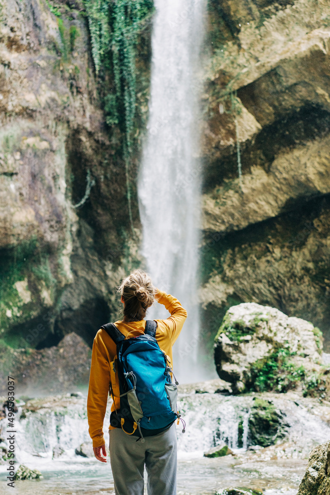 A female hiker hiking near a waterfall stops to look at the view