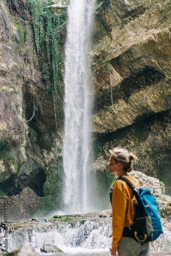 Defocused woman in a canyon with a waterfall in the background.