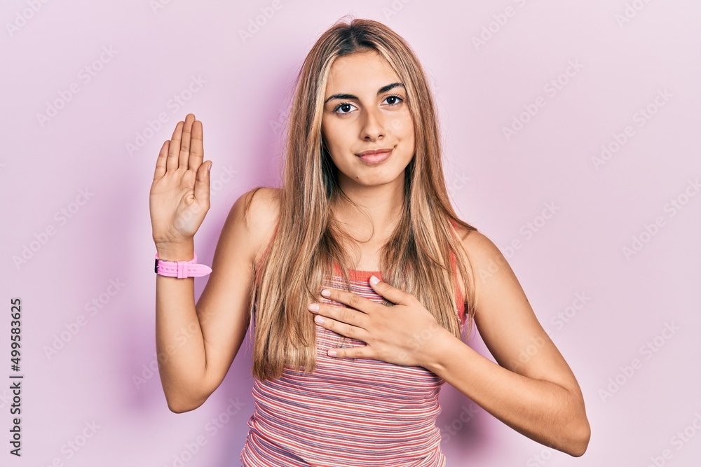 Beautiful hispanic woman wearing casual summer t shirt swearing with hand on chest and open palm, making a loyalty promise oath
