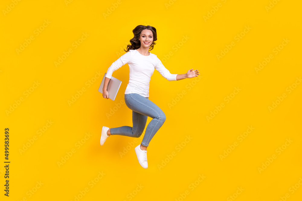 Photo of adorable pretty lady dressed white shirt running jumping holding modern device isolated yellow color background