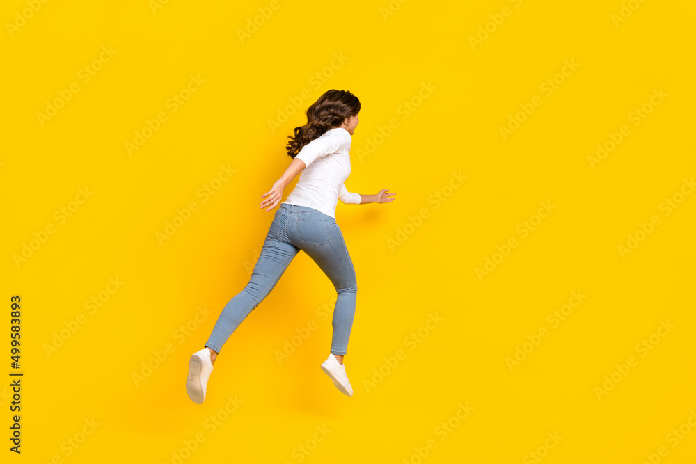 Photo of pretty excited lady dressed white shirt running fast jumping high isolated yellow color background