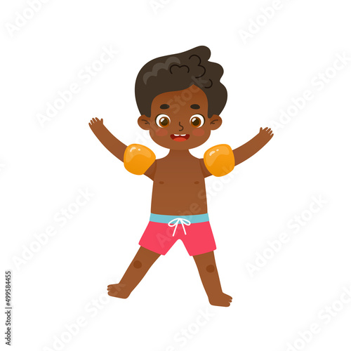 Happy african american boy jumping on the summer vacations. Adorable kid in inflatable armbands.