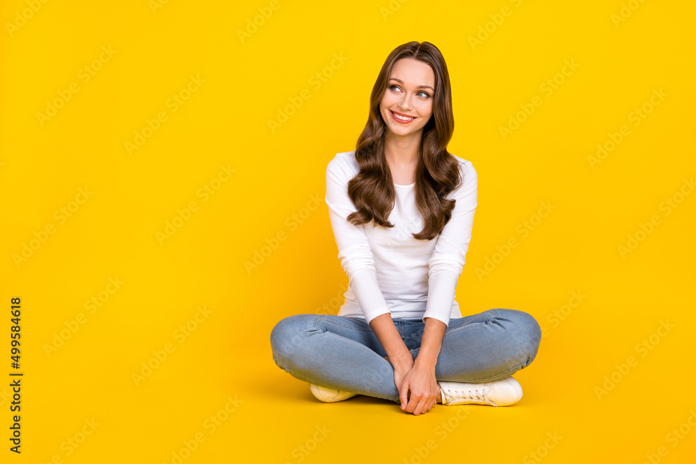 Photo of cute dreamy lady dressed white shirt sitting legs crossed looking empty space isolated yellow color background Photo of cute dreamy lady dressed white shirt sitting legs crossed looking empty space isolated yellow color background