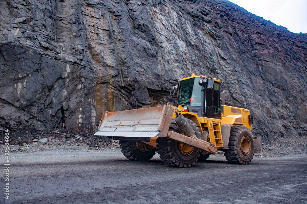 Wheeled bulldozer moves along the roads of an iron ore quarry