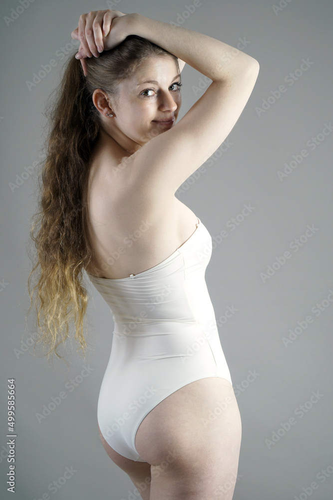 Woman posing in white swimsuit in studio