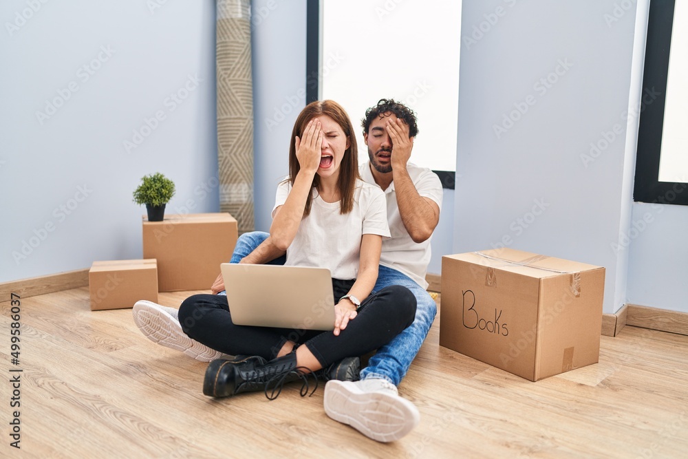 Young couple using laptop at new home yawning tired covering half face, eye and mouth with hand. face hurts in pain. Young couple using laptop at new home yawning tired covering half face, eye and mouth with hand. face hurts in pain.