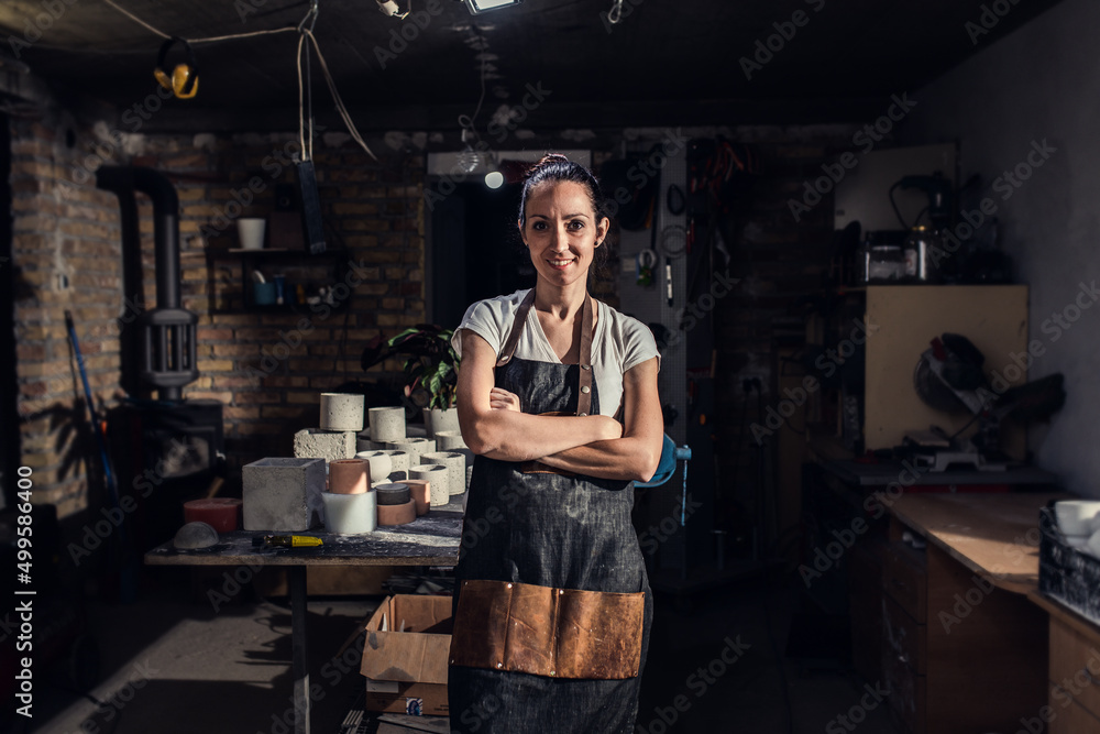 Portrait of craftswoman in apron working in her workshop making decorative concrete vase. Portrait of craftswoman in apron working in her workshop making decorative concrete vase.