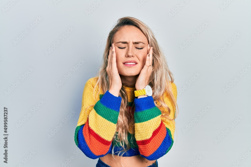Beautiful young blonde woman wearing colored sweater with hand on head, headache because stress. suffering migraine. Beautiful young blonde woman wearing colored sweater with hand on head, headache because stress. suffering migraine.