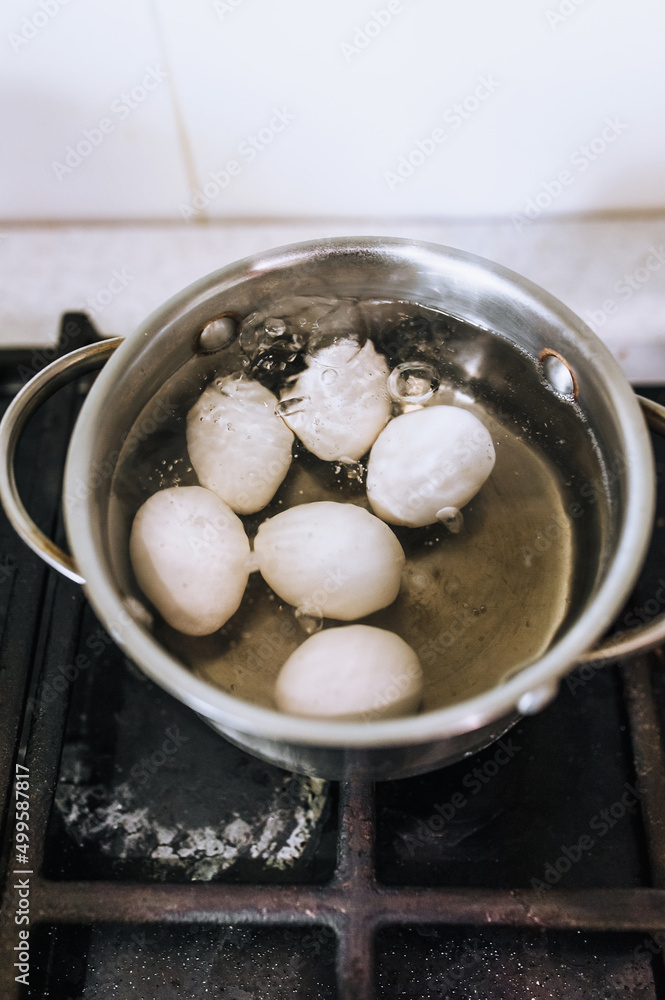 Chicken white eggs are boiled in boiling water in a metal saucepan. Chicken white eggs are boiled in boiling water in a metal saucepan.