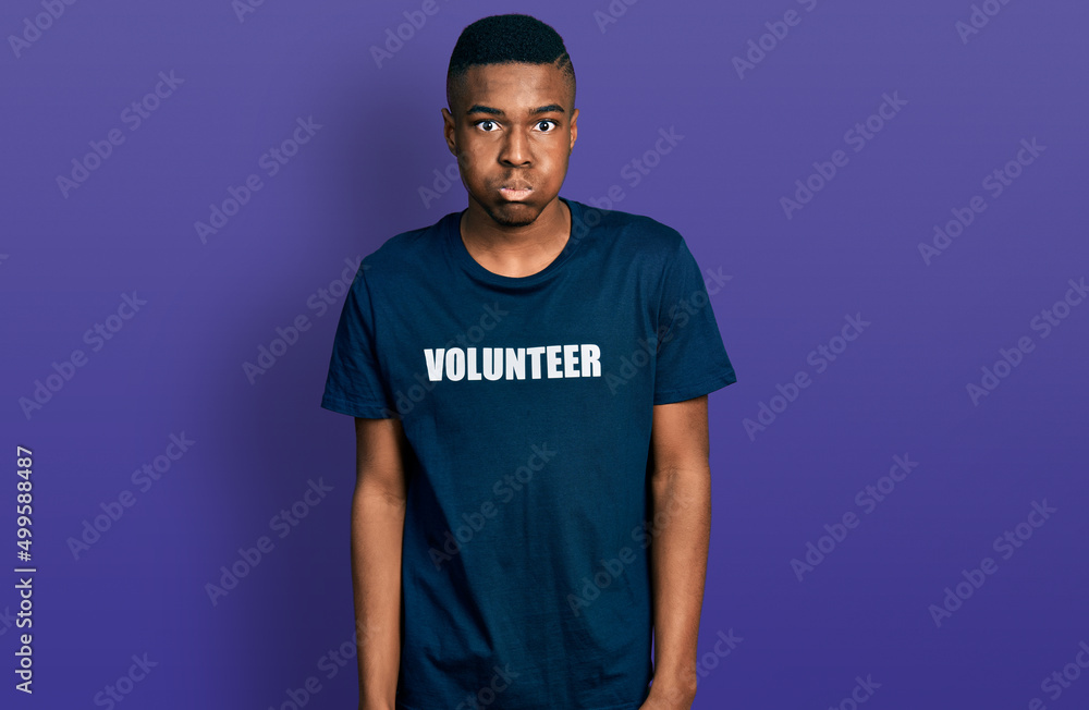 Young african american man wearing volunteer t shirt puffing cheeks with funny face. mouth inflated with air, crazy expression. Young african american man wearing volunteer t shirt puffing cheeks with funny face. mouth inflated with air, crazy expression.