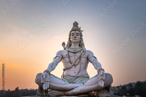 hindu god lord shiva statue in meditation posture with dramatic sky at evening from unique angle photo