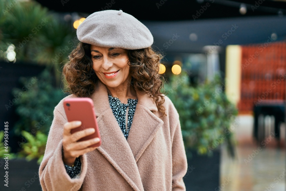 Middle age hispanic woman smiling happy using smartphone at the city. Middle age hispanic woman smiling happy using smartphone at the city.