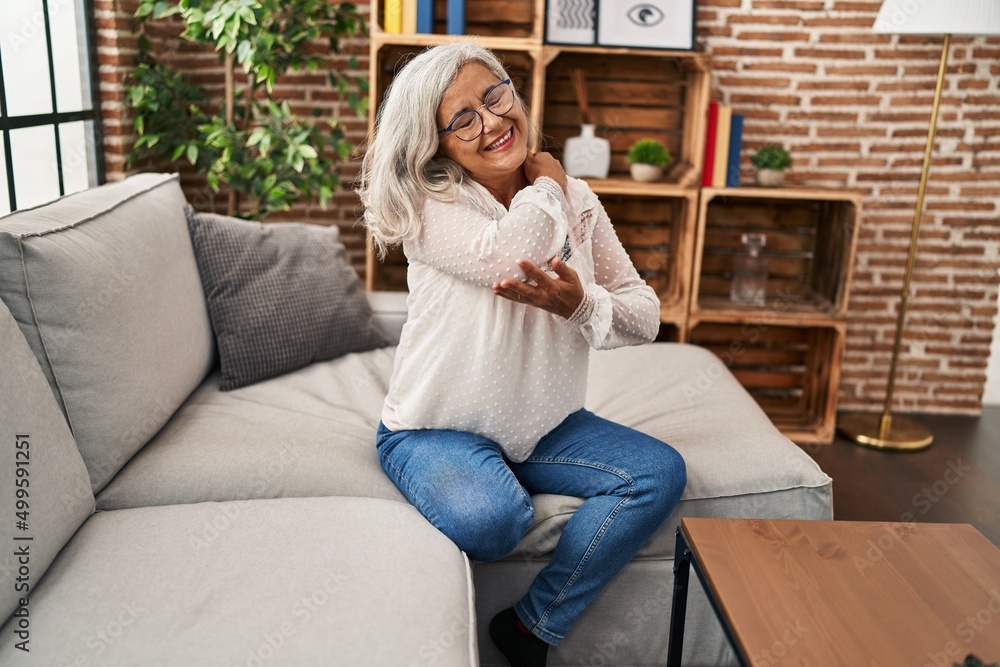 Obraz premium Middle age woman sitting on sofa suffering for back pain at home