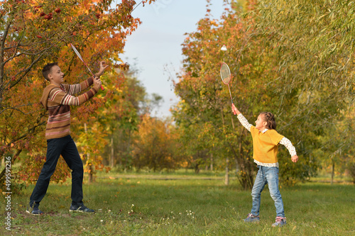 Brother and sister playing badminton in autumn forest