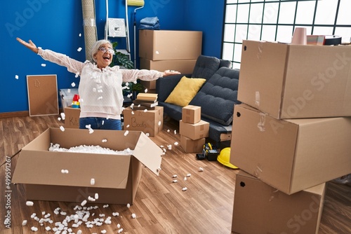 Middle age woman smiling confident throwing foam package at new home