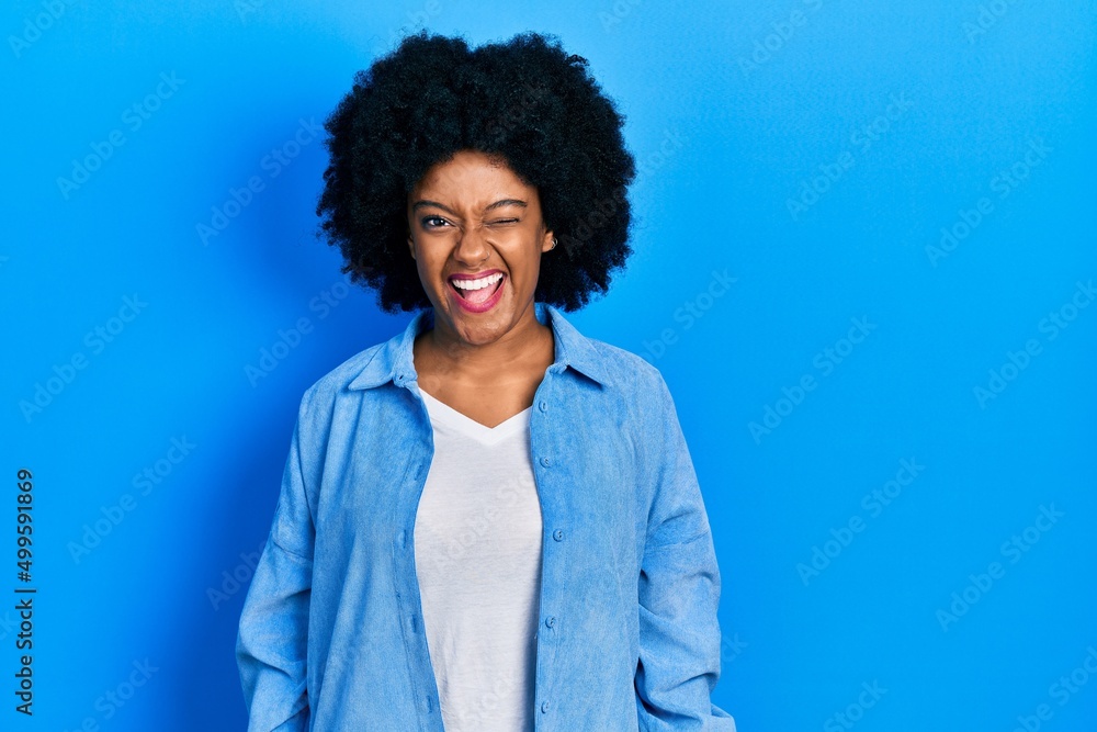Young african american woman wearing casual clothes winking looking at the camera with sexy expression, cheerful and happy face. Young african american woman wearing casual clothes winking looking at the camera with sexy expression, cheerful and happy face.