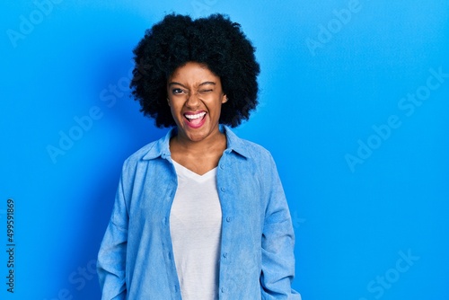 Young african american woman wearing casual clothes winking looking at the camera with sexy expression, cheerful and happy face.