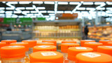 Many bottles of dairy product or juice with orange caps on a supermarket shelf close-up