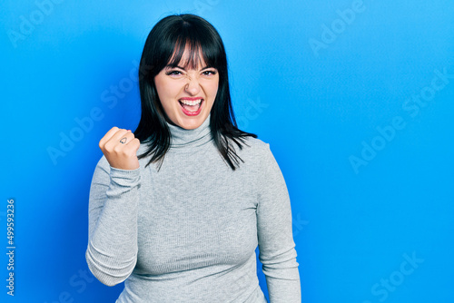 Young hispanic woman wearing casual clothes angry and mad raising fist frustrated and furious while shouting with anger. rage and aggressive concept.