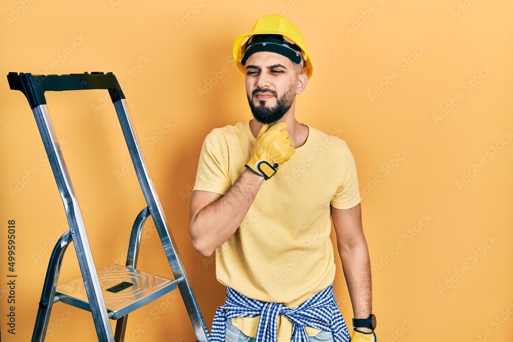 Handsome man with beard by construction stairs wearing hardhat touching painful neck, sore throat for flu, clod and infection