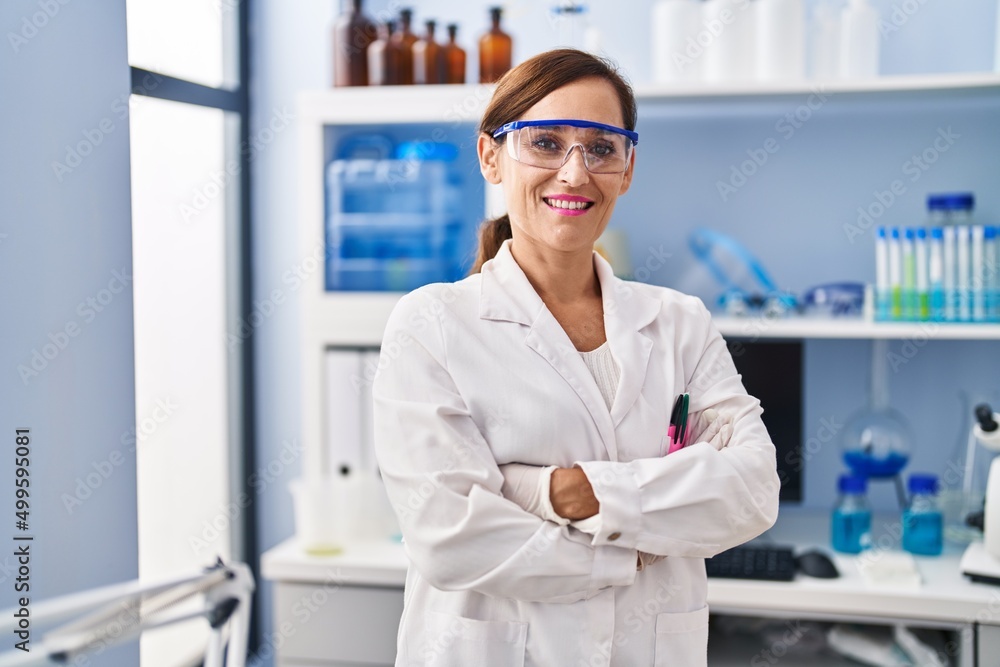 Middle age woman wearing scientist uniform standing with arms crossed gesture at laboratory Middle age woman wearing scientist uniform standing with arms crossed gesture at laboratory