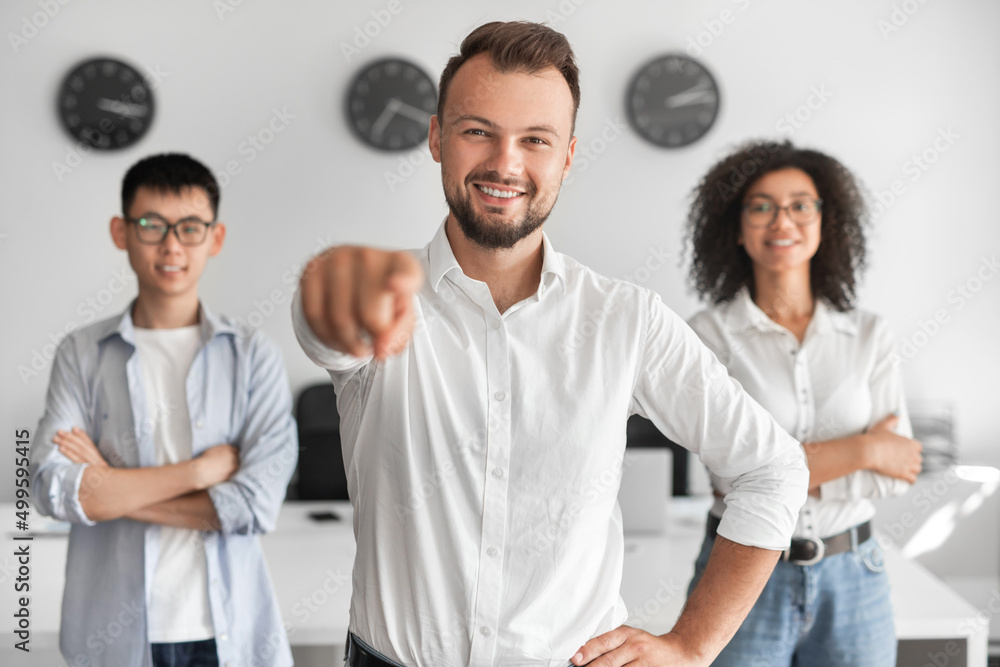 young male manager pointing at camera during work with multiethnic coworkers young male manager pointing at camera during work with multiethnic coworkers