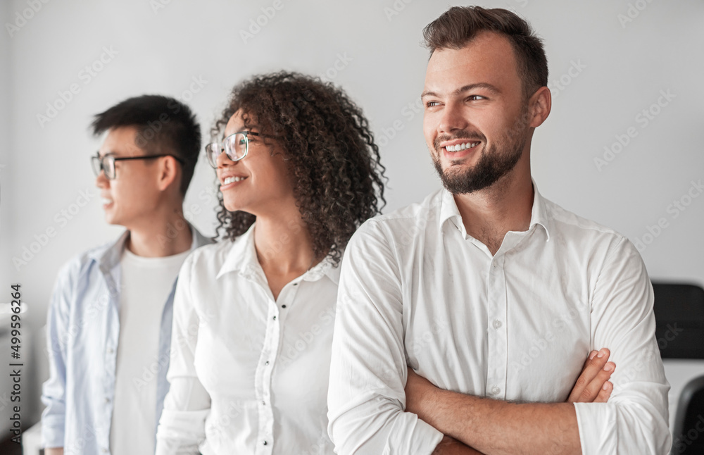 Content young diverse businesspeople looking away in light office Content young diverse businesspeople looking away in light office