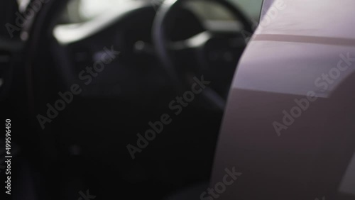 Woman opens the car door and sits inside, close-up. The buyer in the car dealership. Female driver