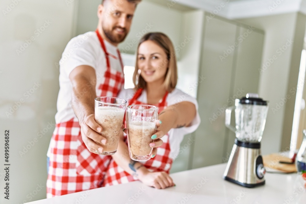 Young couple smiling confident holding glass of smoothie at kitchen Young couple smiling confident holding glass of smoothie at kitchen