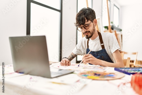 Young hispanic artist man having online paint class at art studio.
