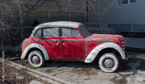 Yakutsk, Sakha Yakutia, Russia - April 17 2022: Old dirty retro car. Red antique car. Antique car in poor condition. Historical concept. Forgotten things. Unnecessary things. Abandoned car.