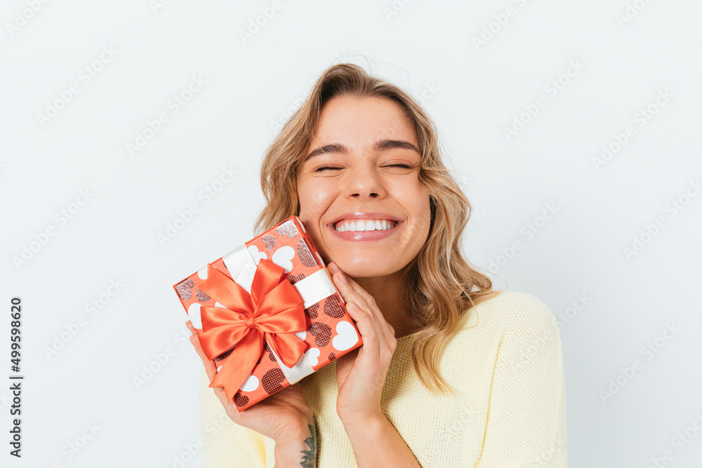 Satisfied happy blonde young woman holding gift box Satisfied happy blonde young woman holding gift box