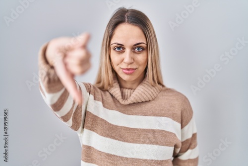 Young blonde woman wearing turtleneck sweater over isolated background looking unhappy and angry showing rejection and negative with thumbs down gesture. bad expression. © Krakenimages.com