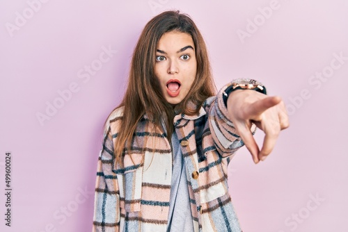 Young caucasian girl wearing casual clothes pointing with finger surprised ahead, open mouth amazed expression, something on the front