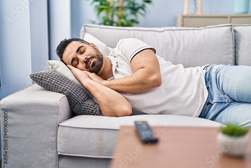 Young hispanic man sleeping on sofa at home