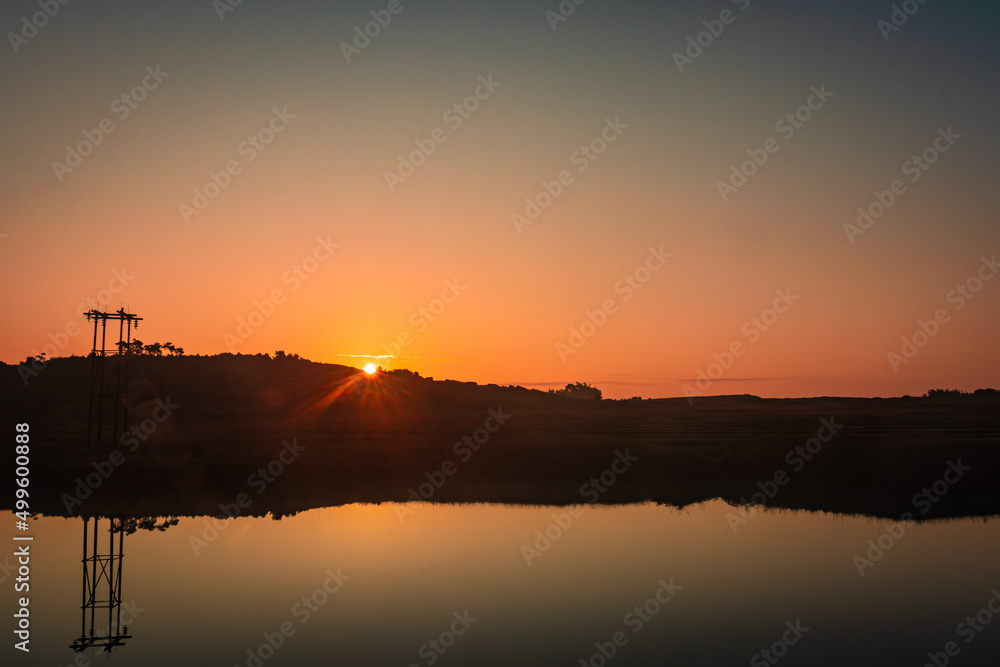 sunrise over mountain shadow and calm lake with reflection at morning from flat angle