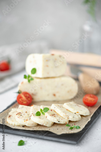 soft homemade cheese with tomatoes and basil on a white table