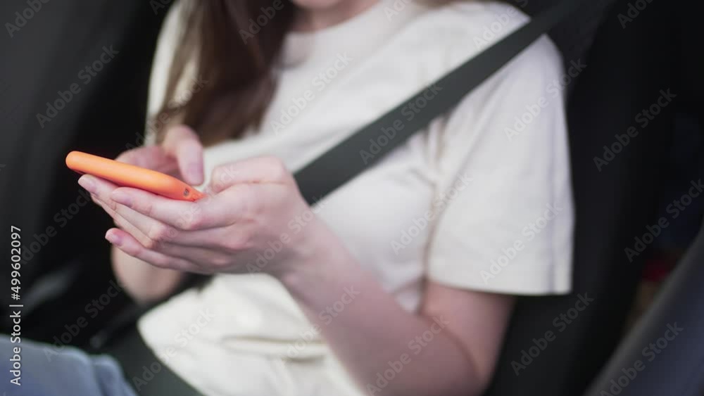 Close-up - unrecognizable woman writes a message buckled up behind the wheel inside a car Close-up - unrecognizable woman writes a message buckled up behind the wheel inside a car