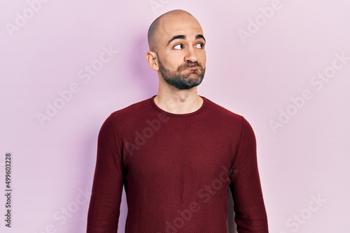 Young bald man wearing casual clothes smiling looking to the side and staring away thinking.