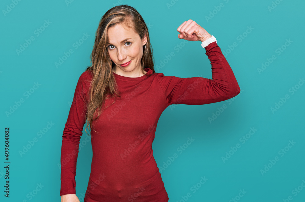 Fototapeta premium Young blonde woman wearing casual clothes strong person showing arm muscle, confident and proud of power