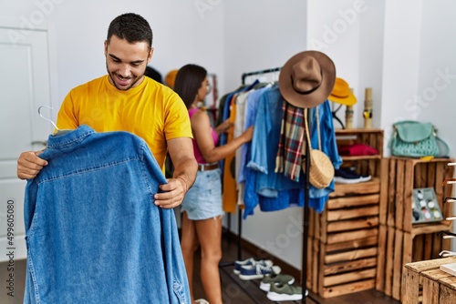 Young latin couple smiling happy choosing clothes at clothing store.