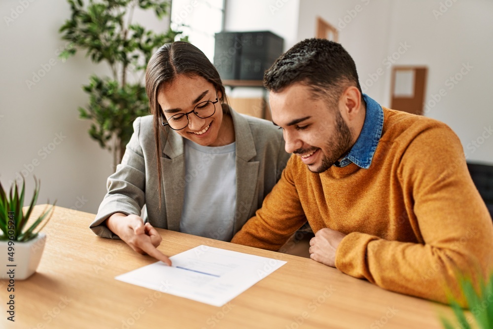 Couple smiling happy reading document at the office. Couple smiling happy reading document at the office.