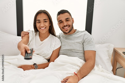 Young latin couple watching tv lying on bed. © Krakenimages.com