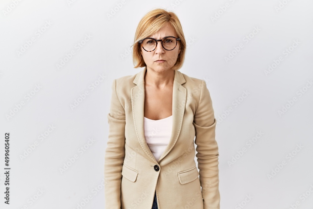 Middle age blonde business woman standing over isolated background skeptic and nervous, frowning upset because of problem. negative person. Middle age blonde business woman standing over isolated background skeptic and nervous, frowning upset because of problem. negative person.