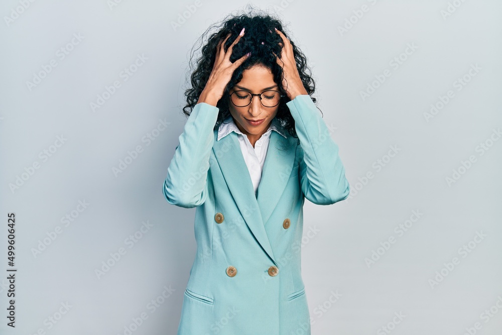 Young latin girl wearing business clothes and glasses suffering from headache desperate and stressed because pain and migraine. hands on head. Young latin girl wearing business clothes and glasses suffering from headache desperate and stressed because pain and migraine. hands on head.