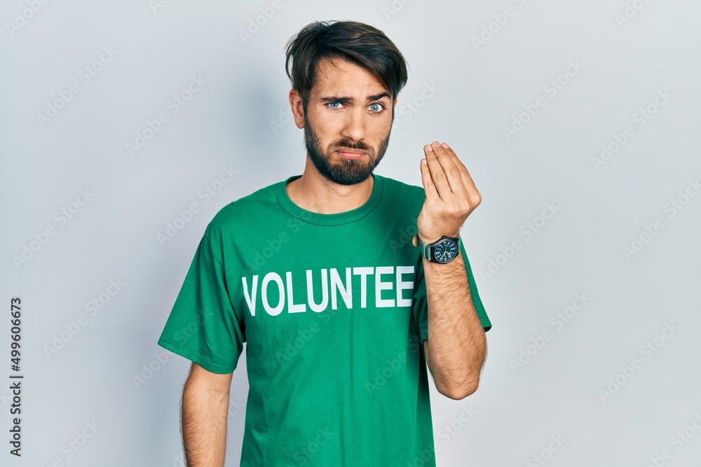 Young hispanic man wearing volunteer t shirt doing italian gesture with hand and fingers confident expression Young hispanic man wearing volunteer t shirt doing italian gesture with hand and fingers confident expression