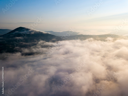 Flight over fog in Ukrainian Carpathians in summer. Mountains on the horizon. Aerial drone view.