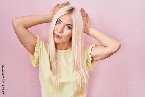 Caucasian woman standing over pink background doing bunny ears gesture with hands palms looking cynical and skeptical. easter rabbit concept.