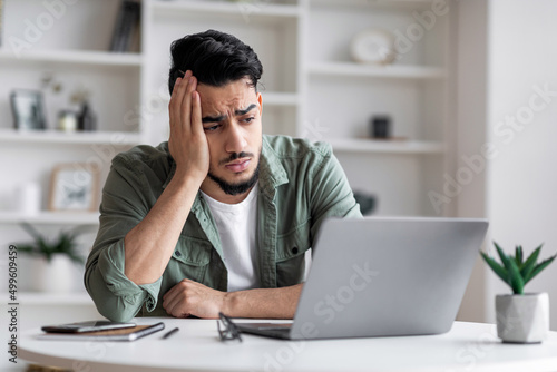 Fototapeta Unhappy attractive millennial muslim male with beard is sad at workplace and loo